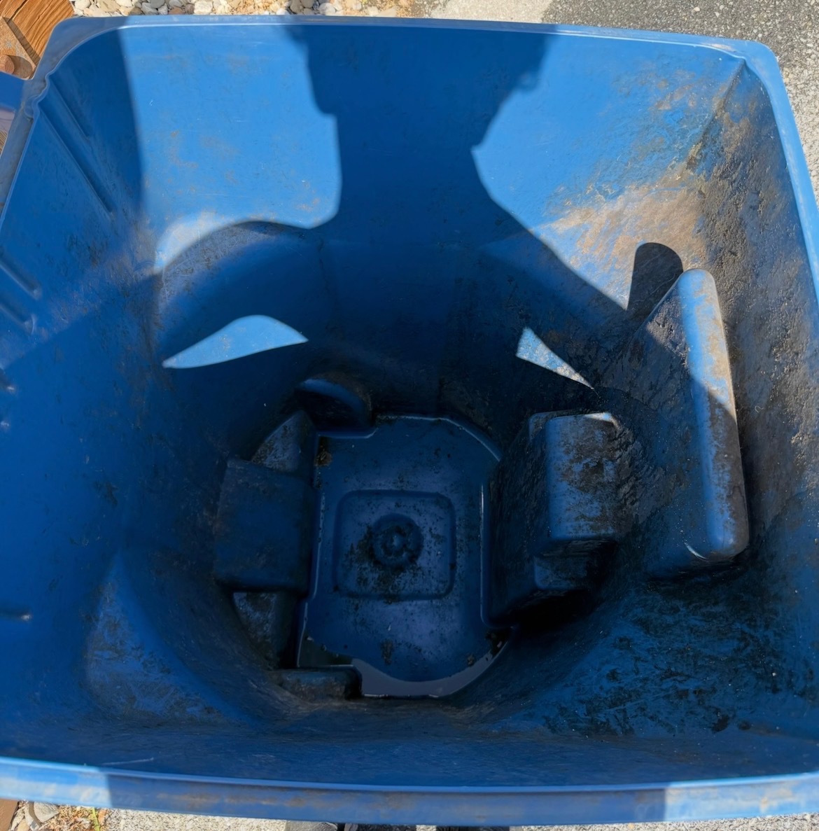 Inside of a trash tote coated in dirt before cleaning
